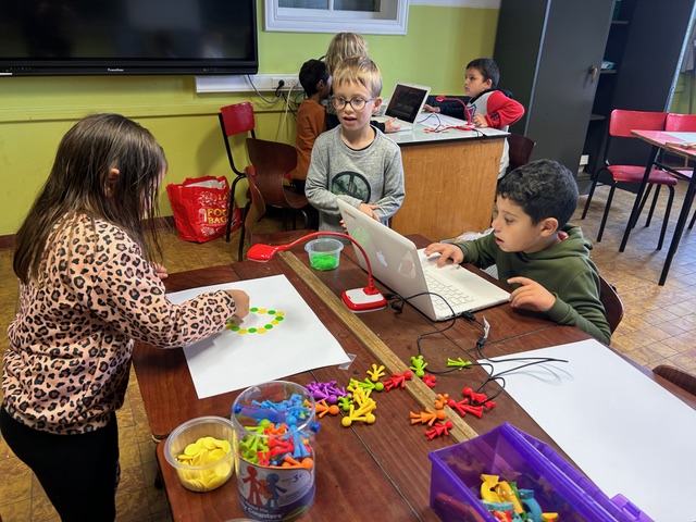 Children in groups in a classroom. They are using the HUE HD Pro camera to animate their own movies through stop motion.