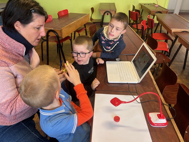 Children in groups in a classroom. They are using the HUE HD Pro camera to animate their own movies through stop motion.