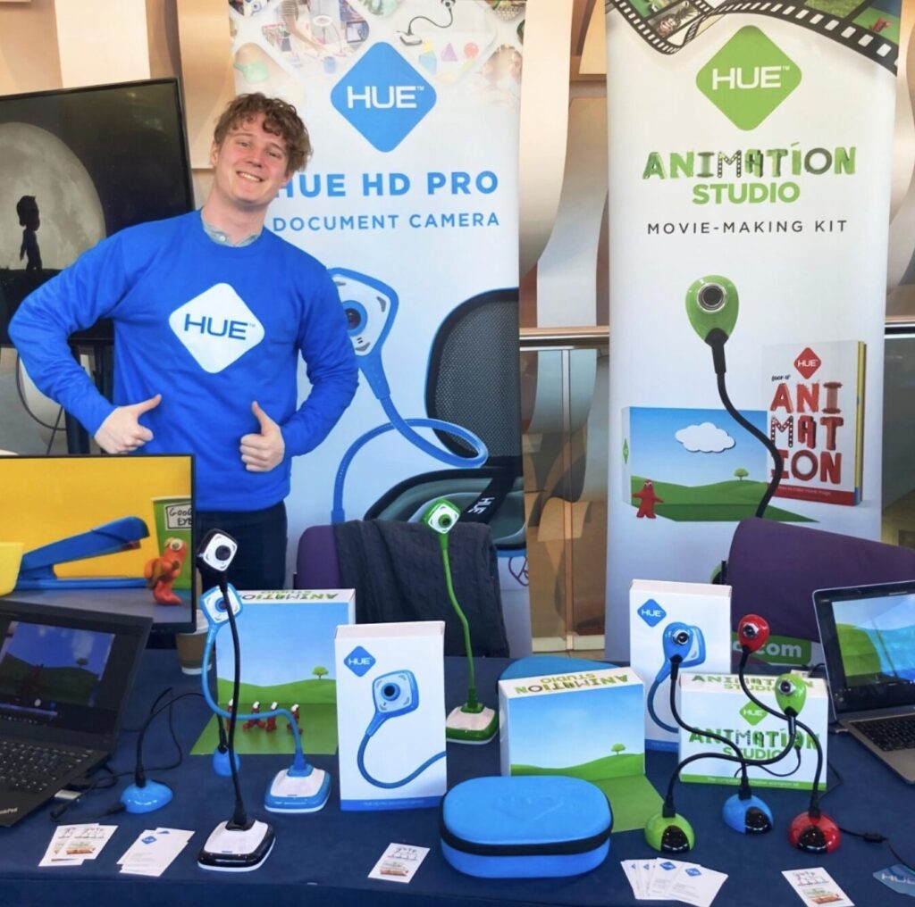 A HUE team member at the HUE booth during a previous show, highlighting the colourful HUE range of cameras, kits and accessories.